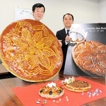 特大の「ガレット・デ・ロワ」を持ち、催しをＰＲする兵庫県洋菓子協会の栗原栄徳副会長（左）ら＝神戸市中央区港島中町６