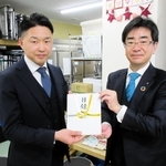 兵庫こども食堂ネットワークの福本大介代表（左）に寄付金の目録を手渡す生命保険協会兵庫県協会の永利謙介会長＝神戸市東灘区深江本町１、同ネットワーク