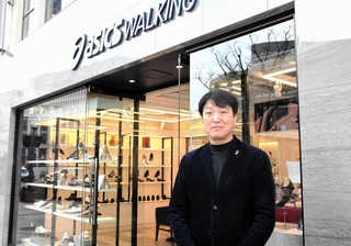 昨年１２月にオープンした「アシックスウォーキング三宮中央通り」の前に立つアシックス商事の小林淳二社長＝神戸市中央区三宮町２