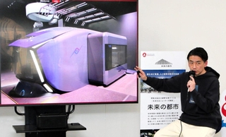 未来の公共交通システムで鉄道車両にキャビンが収まる様子を説明する川崎重工業の天辰祐介プロジェクトリーダー＝神戸市中央区東川崎町１