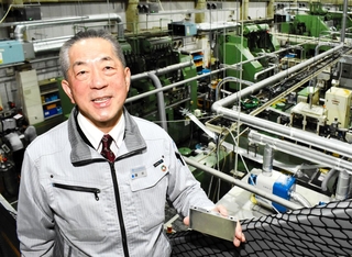 車載用リチウムイオン電池のケースを手にする冨士発條の藤井啓社長＝朝来市和田山町筒江
