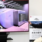 未来の公共交通システムで鉄道車両にキャビンが収まる様子を説明する川崎重工業の天辰祐介プロジェクトリーダー＝神戸市中央区東川崎町１