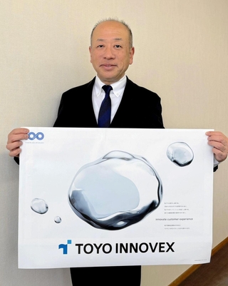 新社名「ＴＯＹＯイノベックス」のポスターを手にする東洋機械金属の田畑禎章社長＝明石市二見町福里