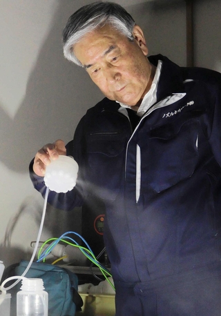噴射口から出る霧を見つめる麻川博良社長。長年の研究開発でこだわってきたのは、液体の粒の小ささ「粒子径」という＝丹波市柏原町柏原
