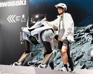 ４本脚で険しい道も走れる未来のモビリティ「コルレオ」の模型とトレイルランナーの上田瑠偉さん＝３日午前、大阪市此花区、夢洲