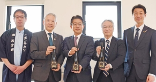 大阪・関西万博に合わせ発売する日本酒を披露したホテル・旅館の社長や日本盛の関係者ら＝西宮市用海町、日本盛