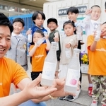 和田岬の子どもたちと一緒に「ワダップル」を手にする平井義也さん＝神戸市兵庫区和田宮通６