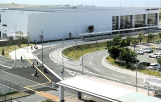 神戸空港の第１ターミナルビルと、第２ターミナルビル（奥）を結ぶ歩道を徒歩で移動する旅客。現在は屋根がない＝神戸市中央区