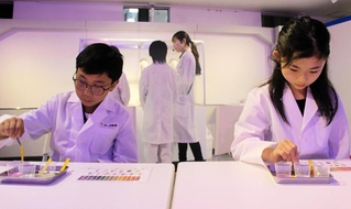 アース製薬のパビリオンで研究者の就業体験を楽しむ小学生たち＝東京都江東区
