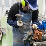 給湯器から銅製の熱交換器を取り出し、さらに分解する作業者（ノーリツ提供）