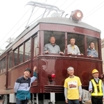 正面と側面の片方が復元された「デ１０１」とまもり隊のメンバーら＝神戸市北区鈴蘭台南町９、神戸電鉄鈴蘭台車庫