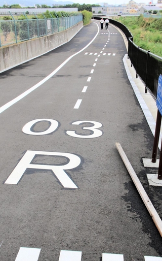 千里川右岸に整備された遊歩道。滑走路を模して北東方向を示す「０３」や右岸を表す「Ｒ」の文字などが入っている＝大阪府豊中市原田中２