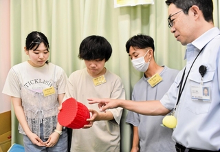 大学生に３Ｄプリンターで製作したちょうちんのゴム製模型を説明する住友ゴム工業の杉本睦樹さん（右）＝神戸市中央区筒井町２