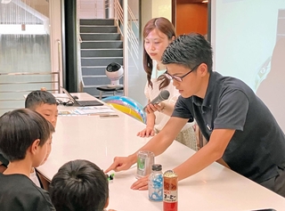 子どもたちにコーヒーの栽培や水素の魅力などについて説明するＵＣＣジャパンと川崎重工業の担当者ら＝神戸市中央区港島中町７、ＵＣＣグループ本社