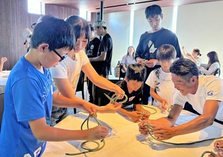「学童ホテル」の体験会で地元の漁師（右端）からロープの結び方を習う小学生ら＝神戸市垂水区海岸通、ホテルセトレ神戸・舞子
