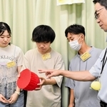 大学生に３Ｄプリンターで製作したちょうちんのゴム製模型を説明する住友ゴム工業の杉本睦樹さん（右）＝神戸市中央区筒井町２