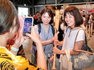 阪神タイガースの大山悠輔選手が実際に使ったバットを持ち、記念写真に納まる来場者＝大阪市此花区の夢洲