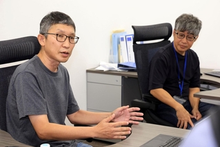 北川進氏の受賞を喜ぶＡｔｏｍｉｓの片岡大取締役ＣＯＯ（左）と浅利大介代表取締役ＣＥＯ＝８日夜、神戸市中央区港島南町７、Ａｔｏｍｉｓ（撮影・丸山桃奈）