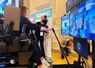 ウクライナ・キーウの会場に置かれた操縦席で神戸の重機を遠隔操作する女性（国土交通省提供）