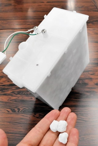 給湯器に内臓されている中和器。容器の中に寒水石が詰められている＝神戸市中央区