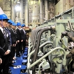 ヘルメット姿で「ルミナス神戸２」のエンジンルームを見学するジャパンエンジンコーポレーションの内定者ら＝神戸港中突堤