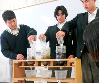 「森林」と「木がない山」、「岩山」に見立てた模型に水を注ぎ、水を蓄える機能を確かめる生徒ら＝神戸市北区大脇台
