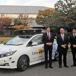 自動運転で経由する白鶴酒造資料館（奥）の前で、使用車両と記念撮影する久元喜造・神戸市長（左端）ら＝神戸市東灘区住吉南町４