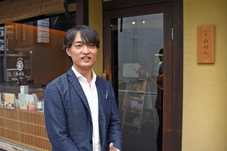 オープン１０周年を迎えた「京都祇園あのん本店」の前に立つサザエ食品の戸島陽平社長＝京都市東山区