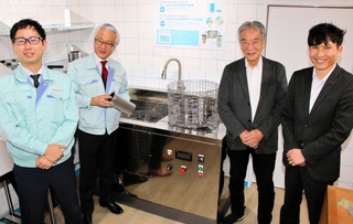 新開発した部品洗浄機を囲む奥谷金網製作所の奥谷智彦社長（左から２人目）ら＝神戸市中央区相生町４