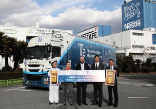 自動運転の出発式に臨むネスレ日本のオリビエ・ロラン・モントゥ常務執行役員（中央）ら＝姫路市香寺町犬飼、同社姫路工場