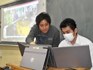 遠隔での溶接を体験する生徒と高丸泰幸専務（左）＝東京都台東区