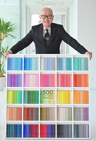 看板商品「５００色の色えんぴつ」と矢崎和彦社長。「世界中のしあわせの情景」から着想を得て、「晴れ渡るタスマンの海の色」など１本１本に色名が付いている＝神戸市中央区新港町（撮影・大田将之）