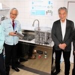 新開発した部品洗浄機を囲む奥谷金網製作所の奥谷智彦社長（左から２人目）ら＝神戸市中央区相生町４