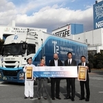 自動運転の出発式に臨むネスレ日本のオリビエ・ロラン・モントゥ常務執行役員（中央）ら＝姫路市香寺町犬飼、同社姫路工場