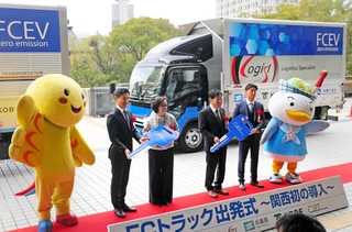 燃料電池小型トラックを背に、出発式に出席した事業者ら＝兵庫県庁