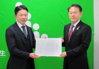 兵庫こども食堂ネットワークの福本大介代表（左）に支援金を贈った生命保険協会兵庫県協会の岡野亮一会長＝神戸市中央区