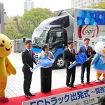 燃料電池小型トラックを背に、出発式に出席した事業者ら＝兵庫県庁