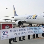 神戸空港の開港20年を祝う横断幕を広げ、搭乗客を見送る空港関係者ら＝20日午前、同空港（撮影・大田将之）