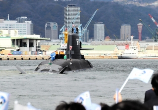 旗を振る関係者らに見送られる潜水艦「ちょうげい」＝１０日午前、神戸市兵庫区和田崎町１、三菱重工業神戸造船所