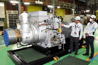 福島第１原発の免震重要棟にあった川崎重工業製ガスタービン発電設備と同シリーズ機。秋平純一課長（左）と永地健郎担当課長が経緯を伝える＝明石市川崎町、同社明石工場