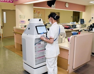 フォーロの胴体部分に検体用の容器を入れ込む看護師＝神戸市中央区楠町７、神戸大病院