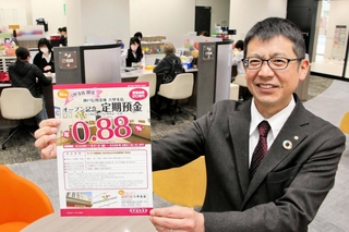 昨年11月にオープンした神戸信用金庫の六甲支店で、優遇金利の定期預金のチラシを持つ井筒篤史次長＝神戸市灘区桜口町４