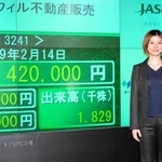 念願だったジャスダック市場への株式上場を果たし、株価モニターの前に立つ友野泉さん＝２００７年２月（ウィル提供）