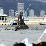 旗を振る関係者らに見送られる潜水艦「ちょうげい」＝１０日午前、神戸市兵庫区和田崎町１、三菱重工業神戸造船所