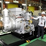 福島第１原発の免震重要棟にあった川崎重工業製ガスタービン発電設備と同シリーズ機。秋平純一課長（左）と永地健郎担当課長が経緯を伝える＝明石市川崎町、同社明石工場