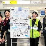 就航１年を記念した手書きのホワイトボードで乗客を迎えたトキエアのスタッフ＝神戸空港