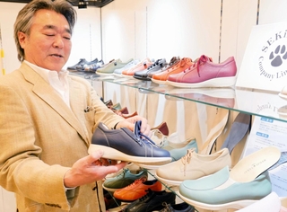 脱ぎ履きしやすい革靴を手にする赤龍化学工業所の高井龍二社長＝神戸市中央区港島中町６