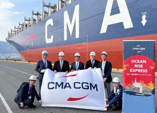 初寄港したコンテナ船の前で記念撮影する関係者ら＝神戸港