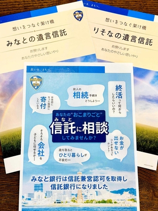 みなと銀行が信託業務を営む認可を受けたことを伝えるチラシ（手前）。パンフレットでも従来（奥右）と異なり、「みなとの遺言信託」と書けるようになった