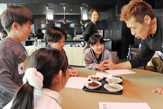 「学童ホテル」の体験会で、淡路市の水産加工会社の社員（右）からイカナゴやちりめんの特徴を教わる児童＝神戸市垂水区海岸通、ホテルセトレ神戸・舞子